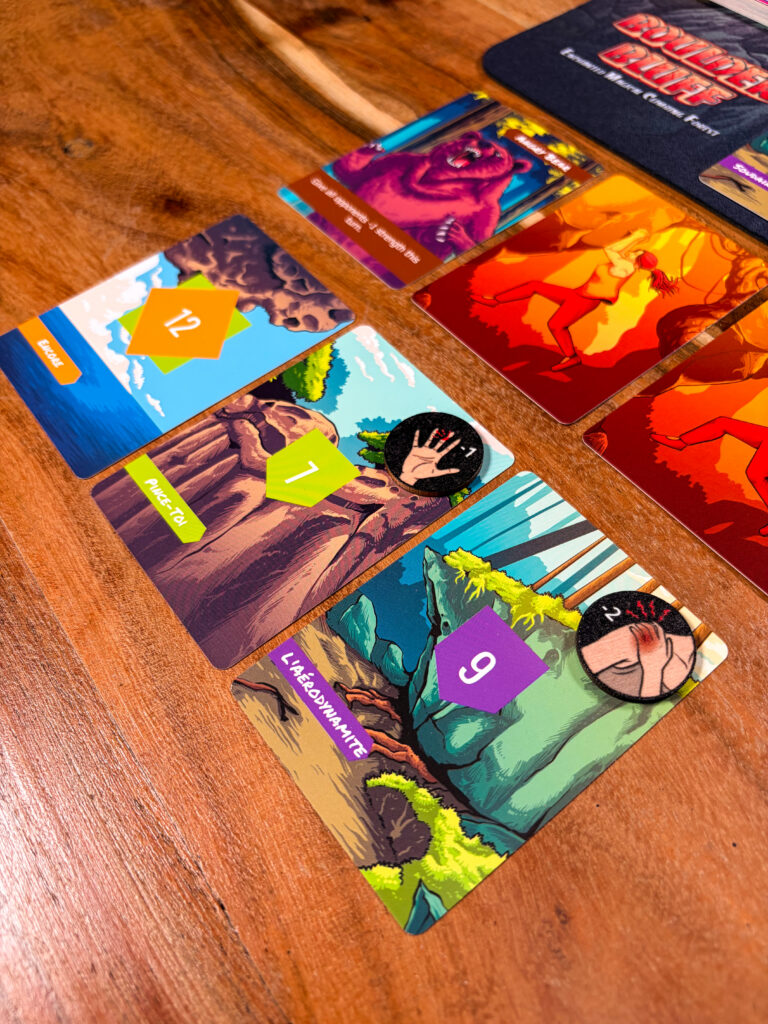Close-up of Boulder Bluff’s illustrated route and climbing cards on a wooden table